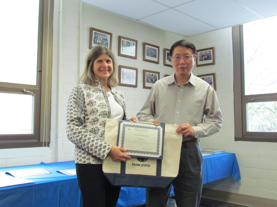 Dr. Carolee Bull (L) presenting the Ten-Year Service Award certificate and Penn State tote bag to Dr. Yinong Yang (R).  Not pictured: Chad Moore and Qin Wang.
