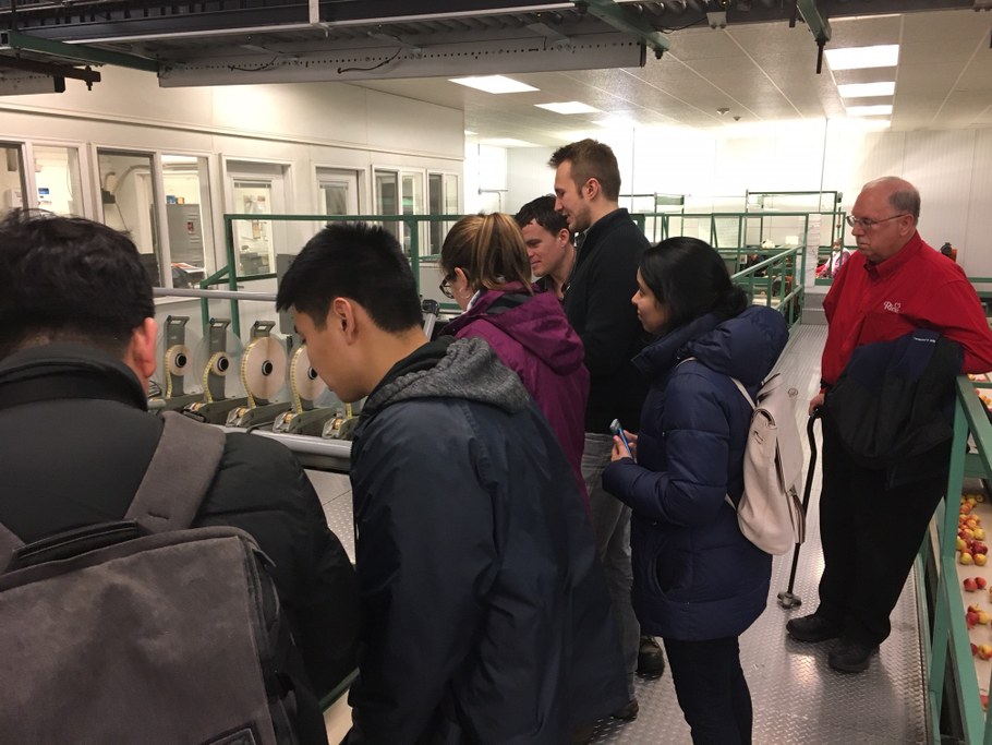 Automated sorting lines at Rice Fruit in which stickers are attached to apples. (L-R) Yongho Jeon, Justin Shih, Laura del Sol Bautista Jalón, Phillip Martin, Rice Fruit engineer, Emma Rosenthal, and Lee Showalter | Image: Kari Peter, Penn State University