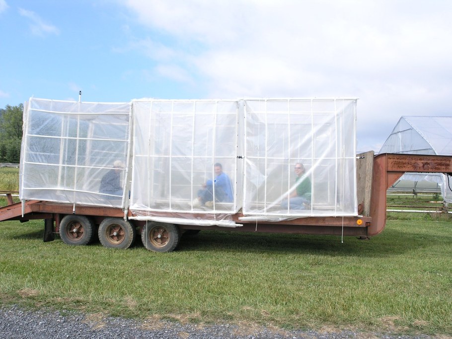 Graduate students sit within the incubation chambers to hold them on the wagon during transportation to the field plots.  Small chambers are sometimes used to further moderate the environmental conditions for some of the wheat inoculation studies.